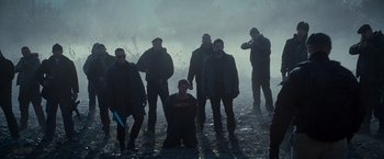 Movie still from “The Expendables 2” (2012), directed by Simon West – A group of people standing in the rain; Wide shot, Low angle