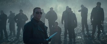 Movie still from “The Expendables 2” (2012), directed by Simon West – A group of men standing in the rain holding a knife; Medium shot, Over the shoulder angle