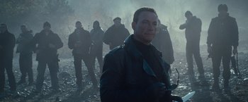 Movie still from “The Expendables 2” (2012), directed by Simon West – A group of men standing in a field; Medium shot, Over the shoulder angle