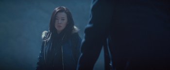 Movie still from “The Expendables 2” (2012), directed by Simon West – A woman in a black jacket looking at a man in a blue jacket; Close Up shot, Over the shoulder angle