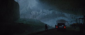 Movie still from “The Expendables 2” (2012), directed by Simon West – Two people are standing in a cave in the dark; Extreme Wide shot, Low angle