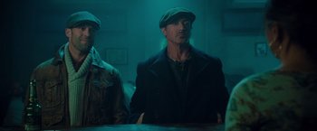 Movie still from “The Expendables 2” (2012), directed by Simon West – A man wearing a green hat and a black jacket; Medium shot, Low angle