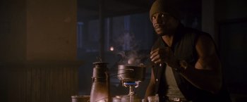 Movie still from “The Expendables 2” (2012), directed by Simon West – A man standing in front of a pot on a stove; Medium shot, Low angle