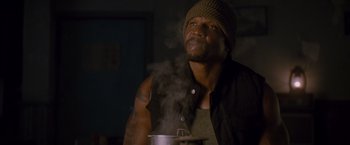 Movie still from “The Expendables 2” (2012), directed by Simon West – A man in a hat is holding a pot; Close Up shot, Low angle