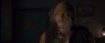 Movie still from “The Expendables 2” (2012), directed by Simon West – A man wearing a hat and a black vest; Close Up shot, Low angle
