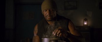 Movie still from “The Expendables 2” (2012), directed by Simon West – A man is cooking something in a pot; Close Up shot, Low angle