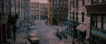 Movie still from “The Expendables 2” (2012), directed by Simon West – An empty street with cars parked on the side of the road; Wide shot, High angle