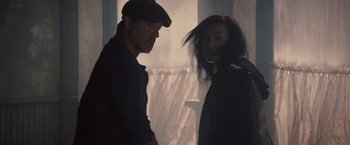 Movie still from “The Expendables 2” (2012), directed by Simon West – A man and a woman standing next to each other; Medium shot, Low angle