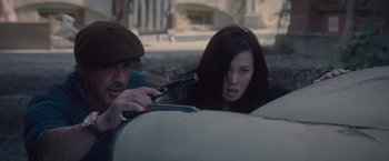 Movie still from “The Expendables 2” (2012), directed by Simon West – A man and a woman in the back of a car; Close Up shot, High angle