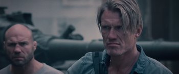 Movie still from “The Expendables 2” (2012), directed by Simon West – A person wearing headphones; Close Up shot, Over the shoulder angle