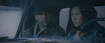 Movie still from “The Expendables 2” (2012), directed by Simon West – A man and a woman sitting in the back of a car; Close Up shot, Low angle