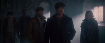 Movie still from “The Expendables 2” (2012), directed by Simon West – Two men are standing in a dark room; Medium shot, Low angle