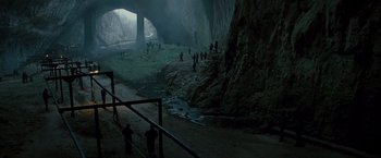Movie still from “The Expendables 2” (2012), directed by Simon West – A group of people standing inside of a cave; Extreme Wide shot, High angle