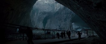 Movie still from “The Expendables 2” (2012), directed by Simon West – A group of people standing in front of a cave; Extreme Wide shot, High angle