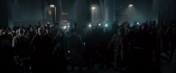 Movie still from “The Expendables 2” (2012), directed by Simon West – A large group of people standing in the dark with lights on their heads; Wide shot, High angle