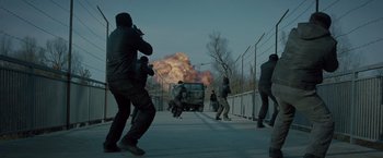 Movie still from “The Expendables 2” (2012), directed by Simon West – A group of men standing next to each other near a fence; Wide shot, Low angle