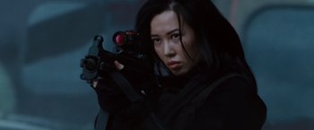 Movie still from “The Expendables 2” (2012), directed by Simon West – A woman holding a gun while standing in the dark; Close Up shot, Low angle