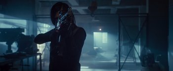 Movie still from “The Expendables 2” (2012), directed by Simon West – A person holding a gun in a room with a window; Medium shot, Low angle