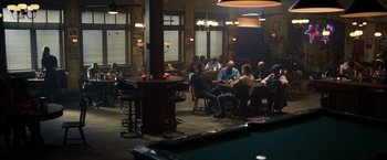 Movie still from “The Expendables 3” (2014), directed by Patrick Hughes – A group of people sitting at a table in a room; Wide shot, High angle