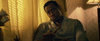 Movie still from “The Expendables 3” (2014), directed by Patrick Hughes – A man sitting on a couch holding a wooden stick; Close Up shot, Low angle