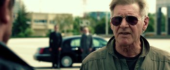 Movie still from “The Expendables 3” (2014), directed by Patrick Hughes – A man wearing sunglasses standing in front of a black car; Close Up shot, Over the shoulder angle