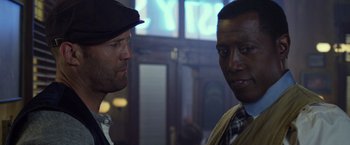 Movie still from “The Expendables 3” (2014), directed by Patrick Hughes – Two men standing next to each other in front of a building; Close Up shot, Over the shoulder angle