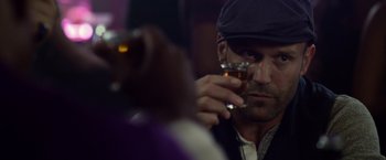 Movie still from “The Expendables 3” (2014), directed by Patrick Hughes – A man holding a glass of beer in his right hand; Close Up shot, Over the shoulder angle
