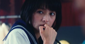 Movie still from “The Forest of Love” (2019), directed by Sion Sono – A young woman with blue eyes is holding her hand to her face; Close Up shot, High angle