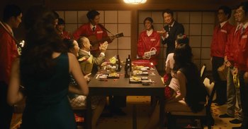 Movie still from “The Forest of Love” (2019), directed by Sion Sono – A group of people sitting at a table with food; Wide shot, Over the shoulder angle
