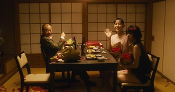 Movie still from “The Forest of Love” (2019), directed by Sion Sono – A group of people sitting at a table with food; Wide shot, High angle
