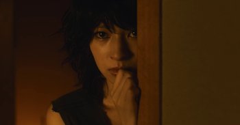 Movie still from “The Forest of Love” (2019), directed by Sion Sono – A woman is leaning against a wall with her hand on her chin; Close Up shot, High angle