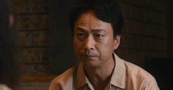 Movie still from “The Forest of Love” (2019), directed by Sion Sono – A person wearing a plaid shirt; Close Up shot, Low angle