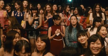 Movie still from “The Forest of Love” (2019), directed by Sion Sono – A group of women standing next to each other in a room; Medium shot, High angle