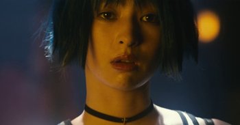 Movie still from “The Forest of Love” (2019), directed by Sion Sono – A person wearing a necklace; Close Up shot, Low angle