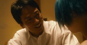 Movie still from “The Forest of Love” (2019), directed by Sion Sono – A man in a white shirt is talking to a woman; Close Up shot, Over the shoulder angle