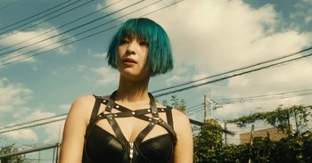 Movie still from “The Forest of Love” (2019), directed by Sion Sono – A woman with blue hair wearing a leather top; Close Up shot, Low angle