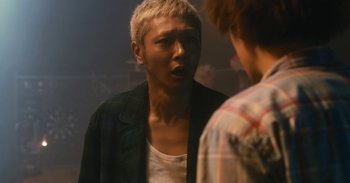 Movie still from “The Forest of Love” (2019), directed by Sion Sono – A young man is talking to another young man; Close Up shot, Over the shoulder angle