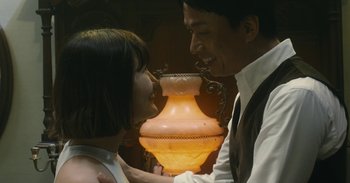 Movie still from “The Forest of Love” (2019), directed by Sion Sono – A man and a woman looking at each other with a lamp; Medium shot, Low angle