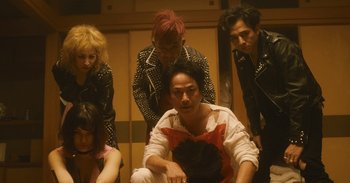 Movie still from “The Forest of Love” (2019), directed by Sion Sono – A group of people standing next to each other in a room; Medium shot, Low angle