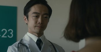 Movie still from “The Forest of Love” (2019), directed by Sion Sono – A man wearing a white lab coat and a tie; Close Up shot, Low angle