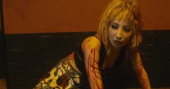 Movie still from “The Forest of Love” (2019), directed by Sion Sono – A woman with blood on her arm and shoulder; Medium shot, High angle