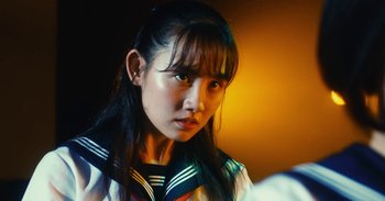 Movie still from “The Forest of Love” (2019), directed by Sion Sono – A young asian woman with long black hair; Close Up shot, Over the shoulder angle