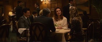 Movie still from “The Glass Castle” (2017), directed by Destin Daniel Cretton – A woman sitting at a table with a glass of white wine; Medium shot, Over the shoulder angle