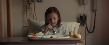 Movie still from “The Glass Castle” (2017), directed by Destin Daniel Cretton – A little girl sitting at a table with a plate of food; Medium shot, High angle