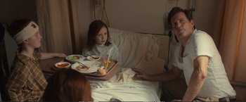 Movie still from “The Glass Castle” (2017), directed by Destin Daniel Cretton – A girl sitting in a hospital bed with a tray of food; Medium shot, Over the shoulder angle