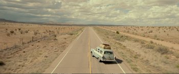 Movie still from “The Glass Castle” (2017), directed by Destin Daniel Cretton – An old car is driving down the middle of the road; Extreme Wide shot, High angle