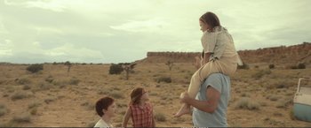 Movie still from “The Glass Castle” (2017), directed by Destin Daniel Cretton – A man carrying a child on his back while standing next to two other children; Wide shot, Over the shoulder angle