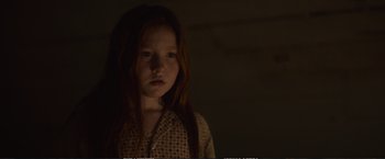 Movie still from “The Glass Castle” (2017), directed by Destin Daniel Cretton – A young girl with long red hair standing in a dark room; Close Up shot, Low angle