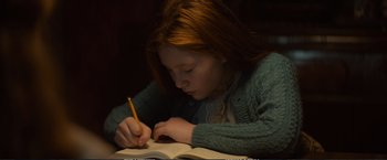 Movie still from “The Glass Castle” (2017), directed by Destin Daniel Cretton – A girl is writing in a book with a yellow pencil; Medium shot, High angle
