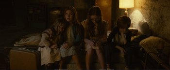Movie still from “The Glass Castle” (2017), directed by Destin Daniel Cretton – A group of young girls sitting on a bench looking at their phones; Medium shot, High angle